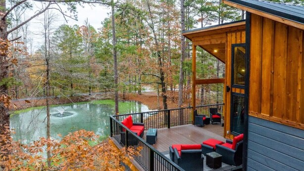 A wooden deck with outdoor seating and a view of a pond. - Dawn's Early Peak - Modern cabin w/ birds-eye view (Smithville)