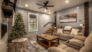 A cozy living room with a fireplace, a Christmas tree, and a staircase leading to another level. - Dawn's Early Peak - Modern cabin w/ birds-eye view (Smithville)