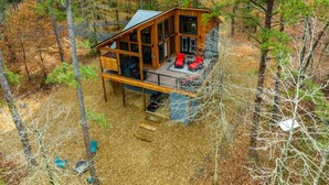 A cabin with a deck, surrounded by trees. - Dawn's Early Peak - Modern cabin w/ birds-eye view (Smithville)