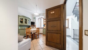 Een keuken met een eettafel, stoelen en een bank. Er is een houten deur met een bordje erboven.