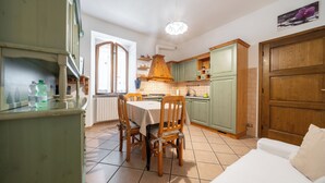 Een keuken met een eettafel, stoelen en kastjes.