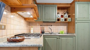 Een keuken met houten kastjes, een gasfornuis en een spoelbak.