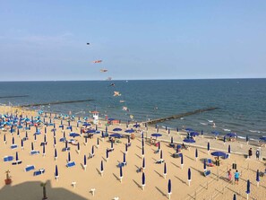 A beach with numerous umbrellas and sun loungers, a lifeguard tower, and a clear view of the ocean. - Studio with pool for 6 people (Caorle)