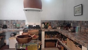 Una cocina con estufa, lavaplatos y diversos utensilios de cocina. Hay cestas, frascos y un tazón de madera grande en la encimera.