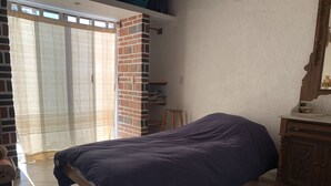 Un dormitorio con cama, un armario de madera, una pared de ladrillo y una ventana con cortinas.