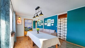 A room with a long table, a sofa, and a painting on the wall. - Deerwood-Holiday Cozy Apartment with Bled Castle View and Pretty Garden (Bled)