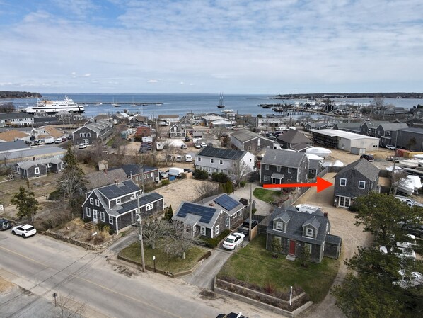Vue aérienne d’une ville côtière avec des maisons d’habitation, une marina et un grand navire de croisière amarré.