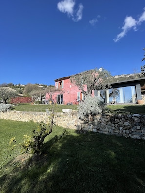 Una casa rosa con un muro de piedra y un jardín.