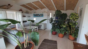 Un salon chaleureux avec un canapé, une table basse et de grandes plantes en pot.