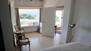 Une chambre à coucher avec un lit, une chaise, un bureau et une vue sur l’extérieur.