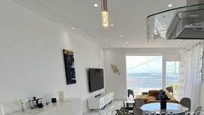A modern living room with a large window offering a view of the sea, a dining area with a round table, and a kitchen with a glass ceiling. - VILLA PHARE CARAIBES (Le Moule)