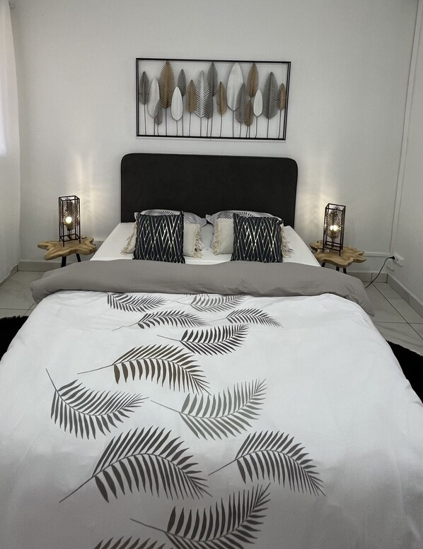 Une chambre à coucher avec un grand lit, deux tables de chevet, une tête de lit et une œuvre d’art accrochée au mur.