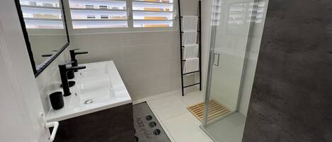 Un bagno moderno con lavandino bianco, rubinetto nero e cabina doccia in vetro.