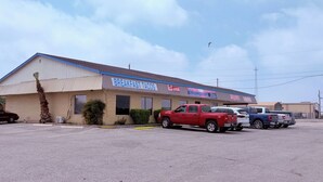 A building with a sign for 'Breakfast Tacos' and a parking lot with several vehicles.