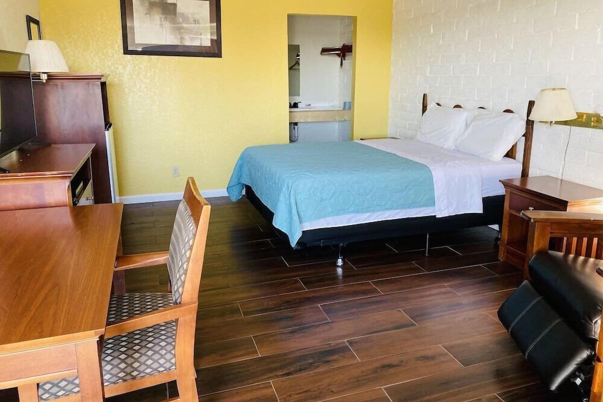 A room with a bed, a desk, a chair, and a mirror.