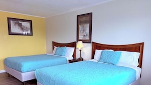 Two twin beds with matching blue bedding, wooden headboards, and a nightstand with a lamp.