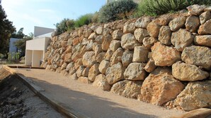 A stone retaining wall with a wooden deck in front.