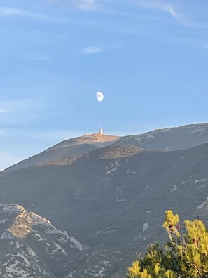 Un paysage de montagne avec un ciel dégagé et une lune visible.