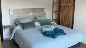 A modern bedroom with a large bed, a wooden headboard, and a built-in wardrobe.