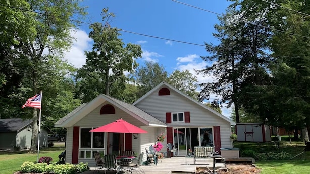 A house with a porch, outdoor furniture, and a flag.