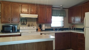 A kitchen with wooden cabinets, a white stove, a microwave, and a refrigerator.