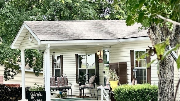 A small, single-story building with a porch, a sign reading "Johnnie Sue's," and a few chairs outside.