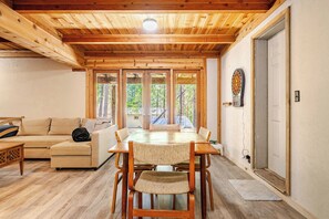 Ein Holzinterieur mit Esstisch, Stühlen, einer Couch und einer Dartscheibe.