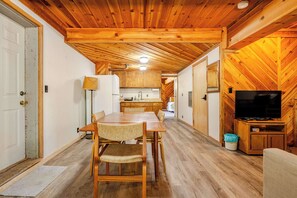 A compact wooden interior with a dining area, kitchenette, and a television. - Spacious Chalet with Game Loft & Pool Access (Arnold)