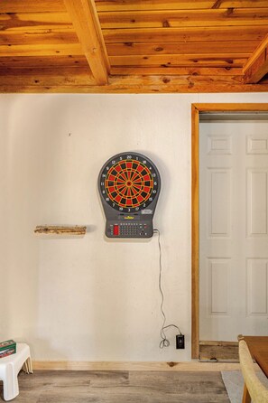 A dartboard mounted on a wall with a wooden ceiling and a white door in the background. - Spacious Chalet with Game Loft & Pool Access (Arnold)