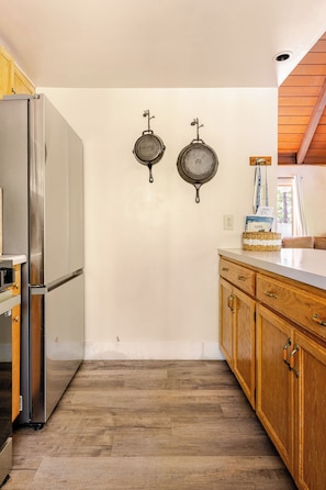 A kitchen with wooden cabinets, a stainless steel refrigerator, and two hanging pans. - Spacious Chalet with Game Loft & Pool Access (Arnold)