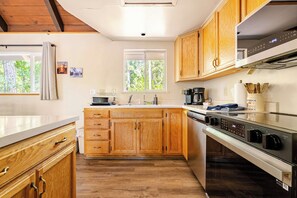 A modern kitchen with wooden cabinets, a stainless steel stove, and a window providing natural light. - Spacious Chalet with Game Loft & Pool Access (Arnold)