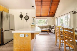 Une cuisine avec un îlot central en bois, un réfrigérateur et un coin repas comprenant une table et des chaises en bois.