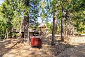 A rustic cabin with a wooden deck and a metal utility box in a forested area. - Spacious Chalet with Game Loft & Pool Access (Arnold)
