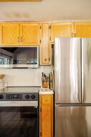 A kitchen with wooden cabinets, a stainless steel refrigerator, a stove, and a microwave. - Spacious Chalet with Game Loft & Pool Access (Arnold)