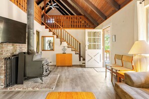 Un salon spacieux doté d’une cheminée, d  ’un escalier en bois et d’un coin salon confortable.