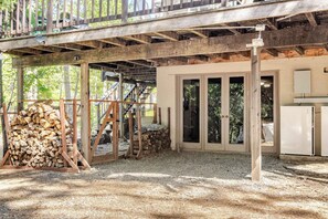 A rustic cabin with a wooden deck, a staircase leading to a loft, and a pile of firewood. - Spacious Chalet with Game Loft & Pool Access (Arnold)