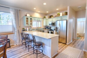 A modern kitchen with a large island, bar stools, stainless steel appliances, and light blue cabinets. - Beautiful, upgraded home in the heart of Pinetop, Woodland Lake area (Pinetop-Lakeside)