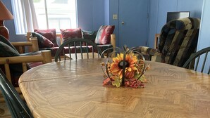Une table de salle à manger ronde en bois, agrémentée d’un centre de table floral, et entourée de chaises.