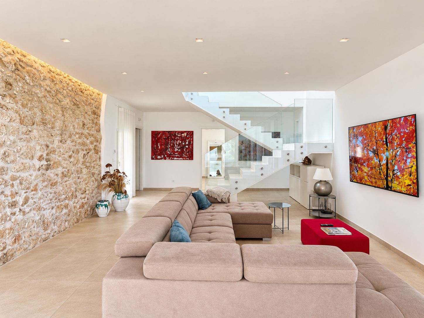 Ein modernes Wohnzimmer mit einem großen Ecksofa, einer Treppe und einer Steinwand.