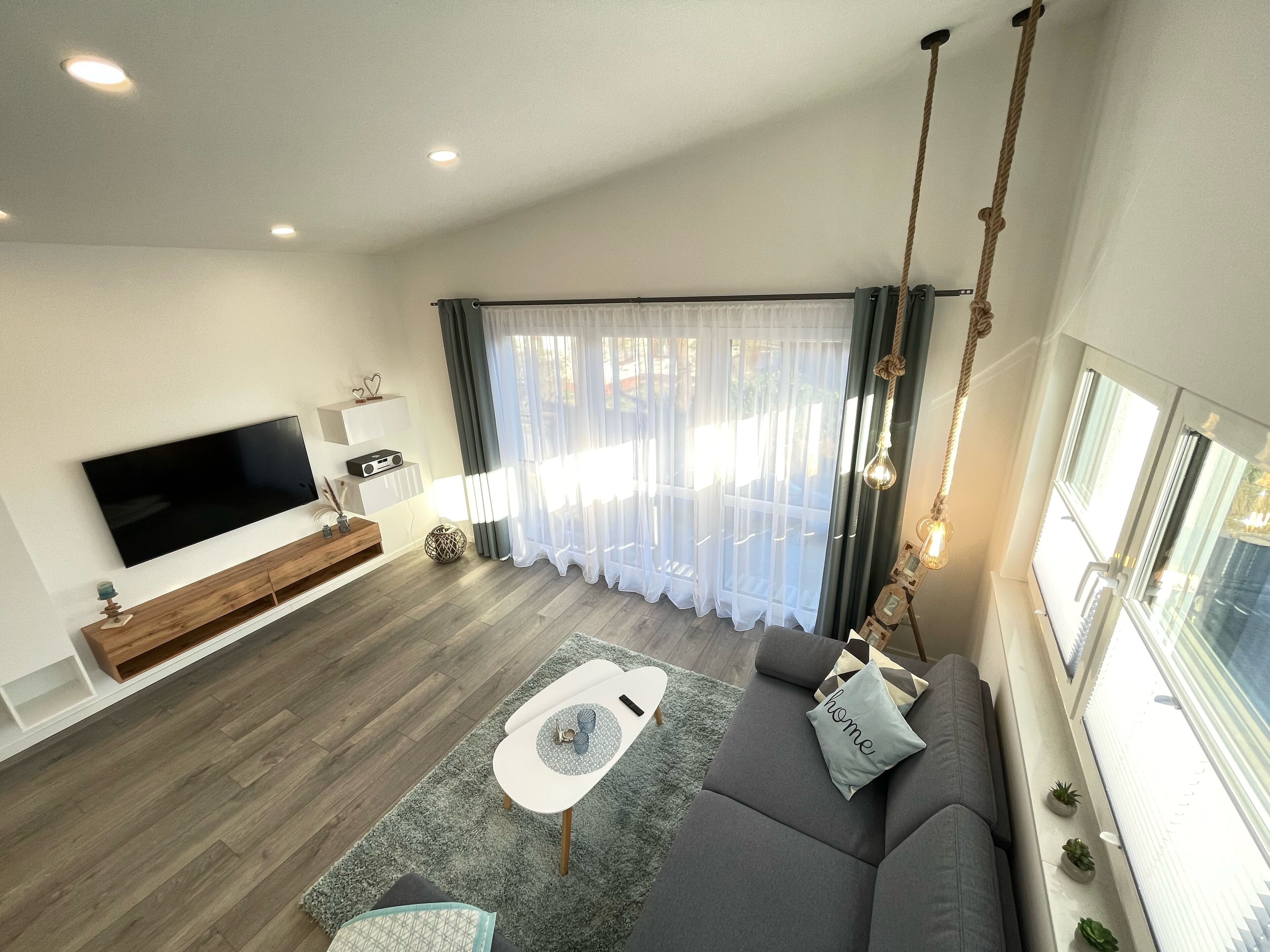 A modern living room with a flat-screen TV, grey sofa, and a coffee table.