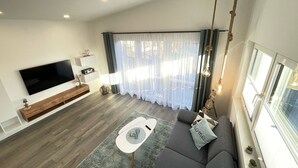 Ein modernes Wohnzimmer mit Flachbildfernseher, grauem Sofa und Couchtisch.