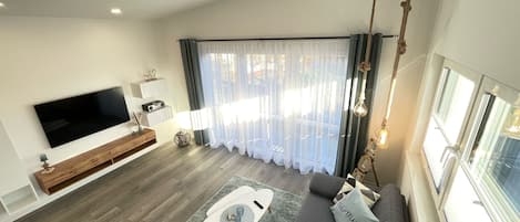 A modern living room with a flat-screen TV, grey sofa, and a coffee table.
