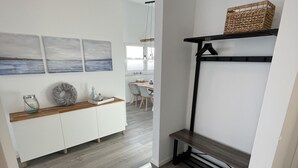 Ein modernes Interieur mit Holzboden, weißen Wänden und einem Essbereich im Hintergrund.