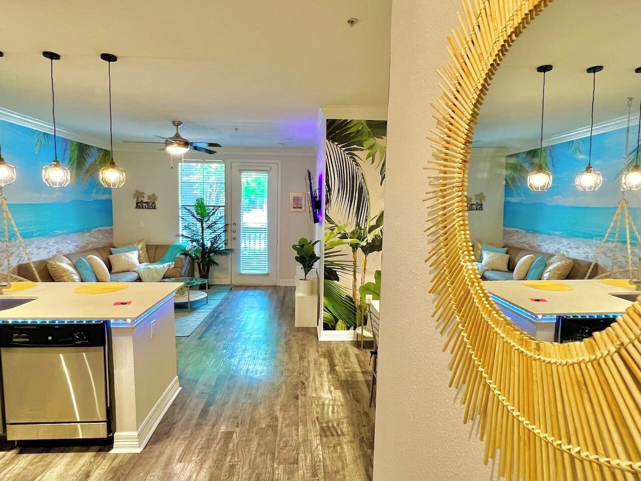 A modern kitchen with a central island, pendant lighting, and a large mirror with a bamboo frame.