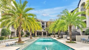 Una piscina rodeada de palmeras y edificios modernos.