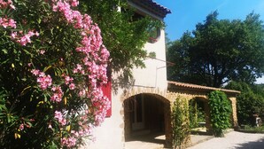 Ein traditionelles Steinhaus mit roter Tür, Bogenportal und kleinem Balkon.