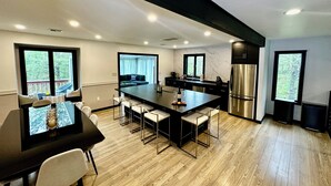 Una cocina moderna con una isla central, electrodomésticos de acero inoxidable y un comedor con mesa y sillas.