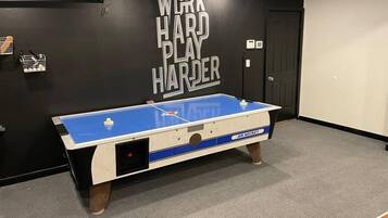 A pool table in a room with a black wall featuring the text "WORK HARD PLAY HARDER".
