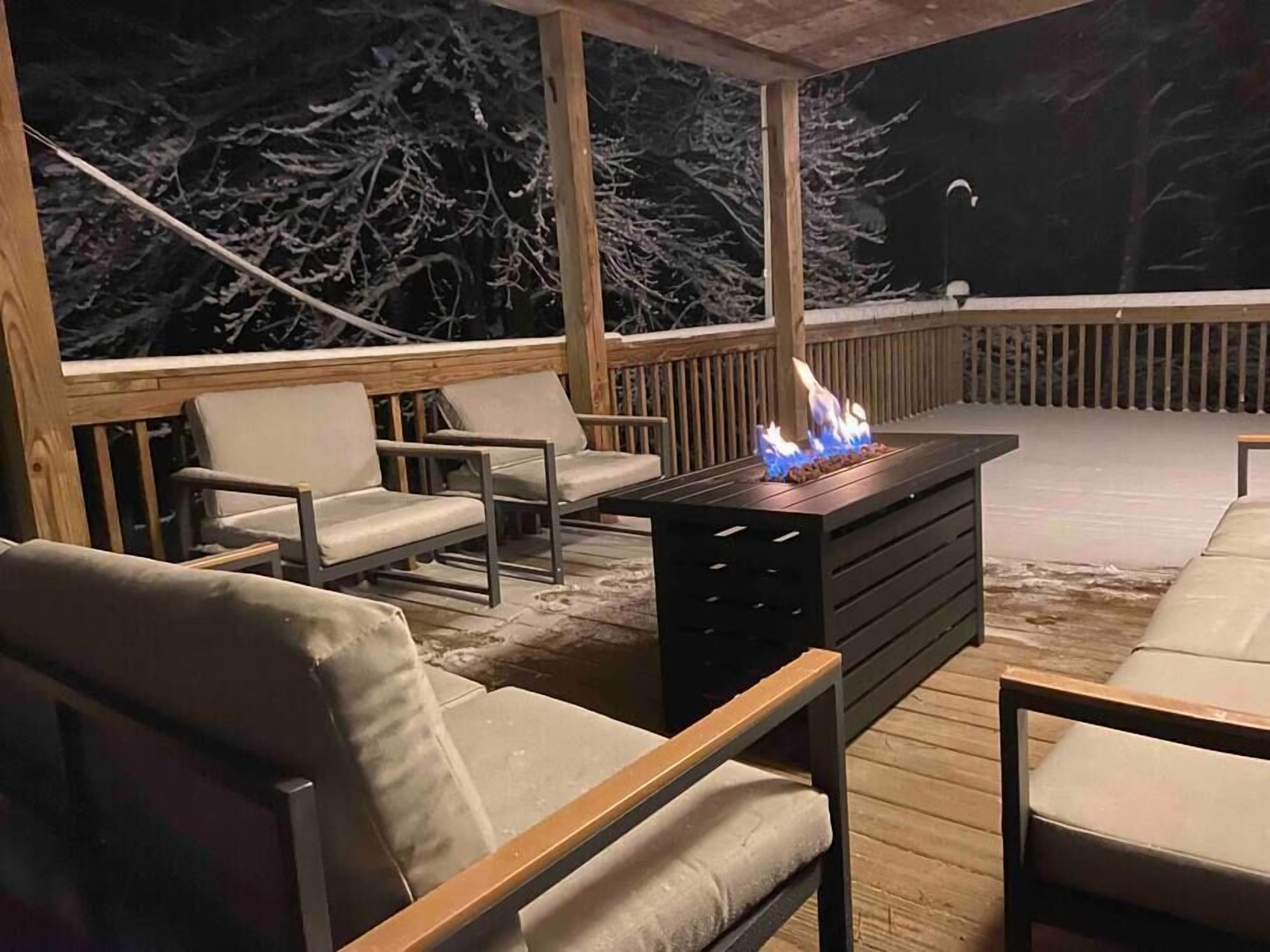 An outdoor deck with wooden furniture and a built-in fire feature.