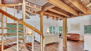 A spacious room with a wooden staircase, a bed, a white cabinet, and a leather sofa. - Hidden Getaway Pool Home on 1.5 acres near all. Sleeps 17. Pool, ping pong etc. (Fort Lauderdale)